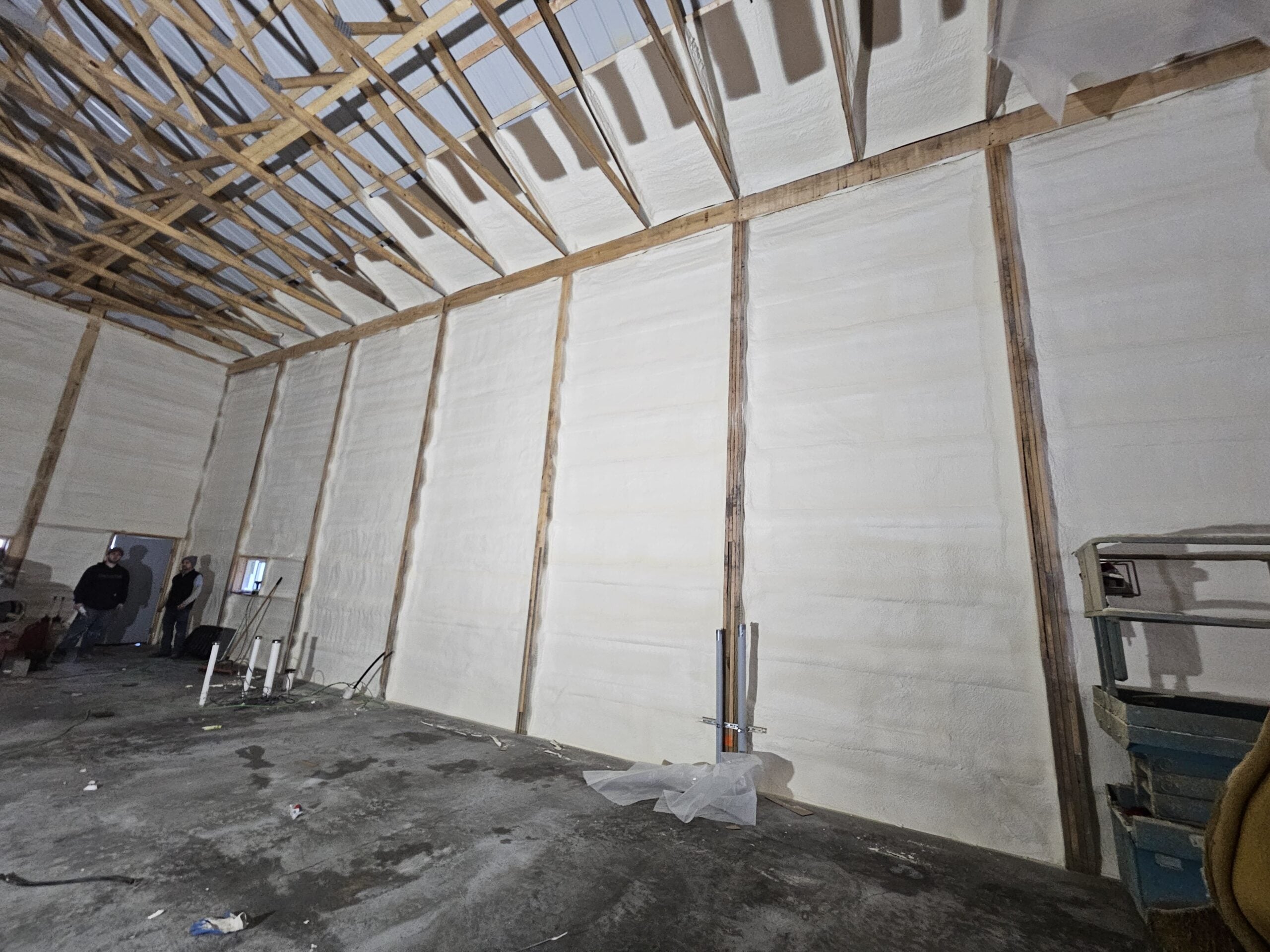 Pole barn with crew members visible thick white spray foam on all walls