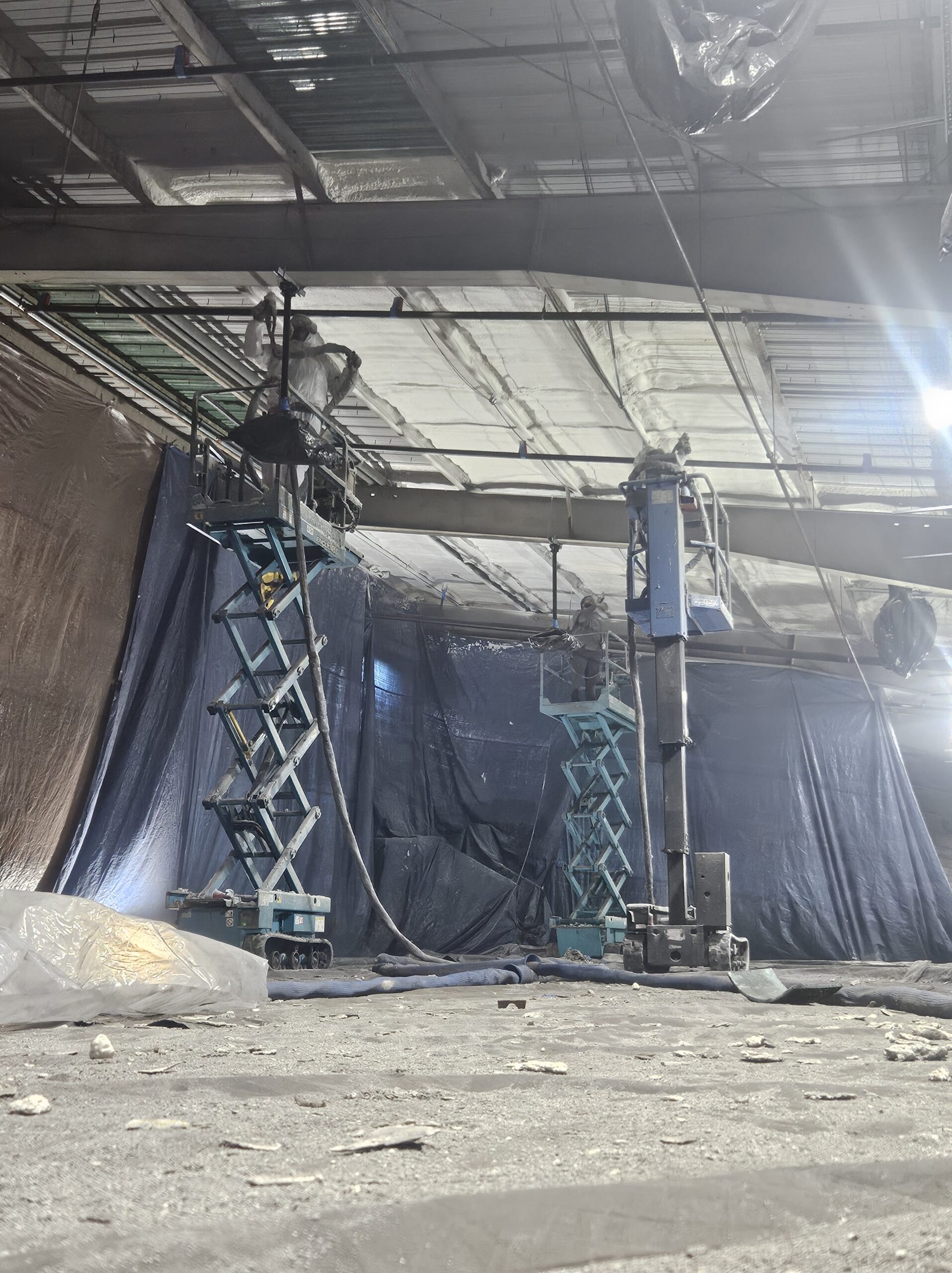 Spray foam insulation specialists applying closed-cell foam across large commercial building ceiling in Iowa