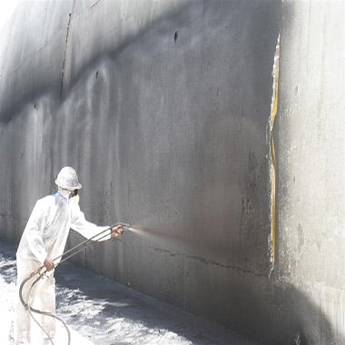 Worker spraying fluid applied membrane onto concrete foundation wall – Upper Midwest foundation waterproofing specialists TCS